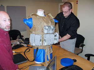 Dr. Evan Goldman (l) and John Ficker of Edge (r) adjust mockup of vest and body armor for testing sensor system