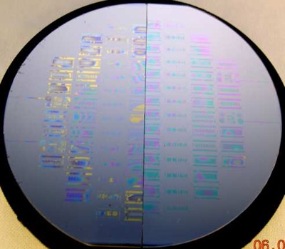 Fig. 6: Left half of wafer (TiW/Au seed) shows an example of solder spill out after bonding as caused by de-wetting of solder. Notice that the pressure non-uniformity is evident by observing that the spill out is most severe on the outer ring of the wafer and much less towards the center. Right half of wafer (Nb/Au seed) shows an example of well bonded wafers with no solder spill outs. The pressure nonuniformity is not evident on the right side. wafer bonding